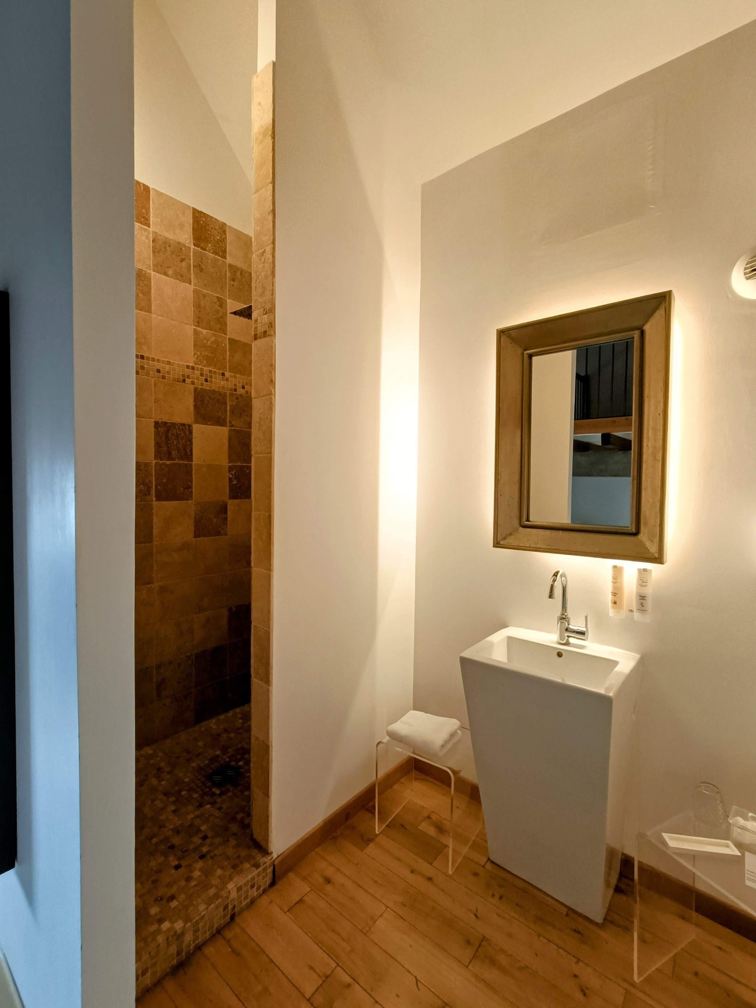 A modern bathroom with a shower, a sink, and a mirror.