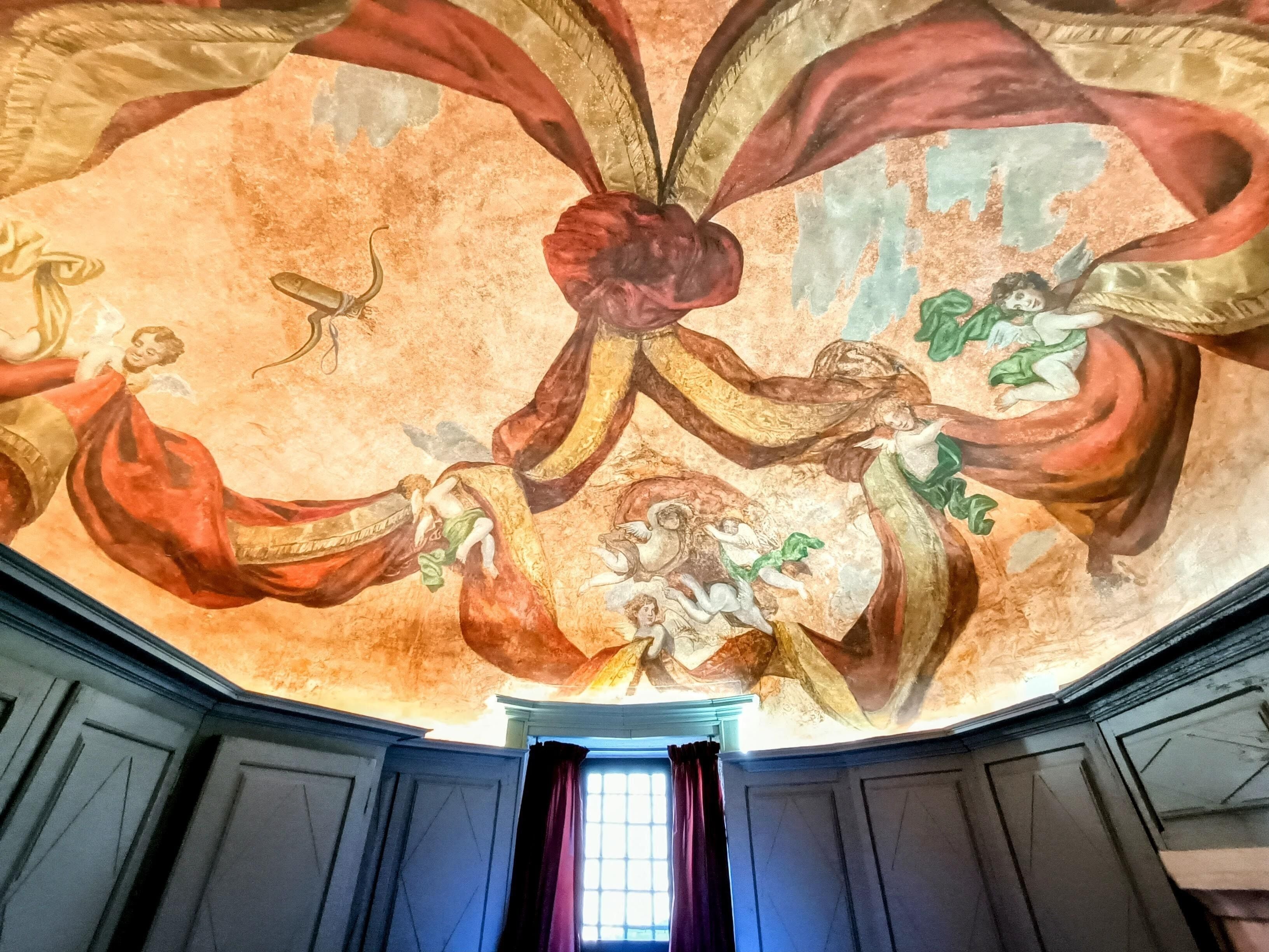 A room with a high ceiling featuring a detailed fresco mural.