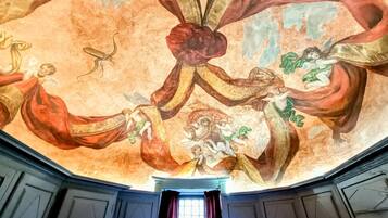 A room with a high ceiling featuring a detailed fresco mural.