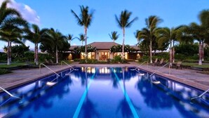A swimming pool with a clear blue water surface, surrounded by palm trees and a building with a tiled roof. - Stunning 4  bed, 3 1/2 bath Mauna Lani home near beach, golf (Waimea)