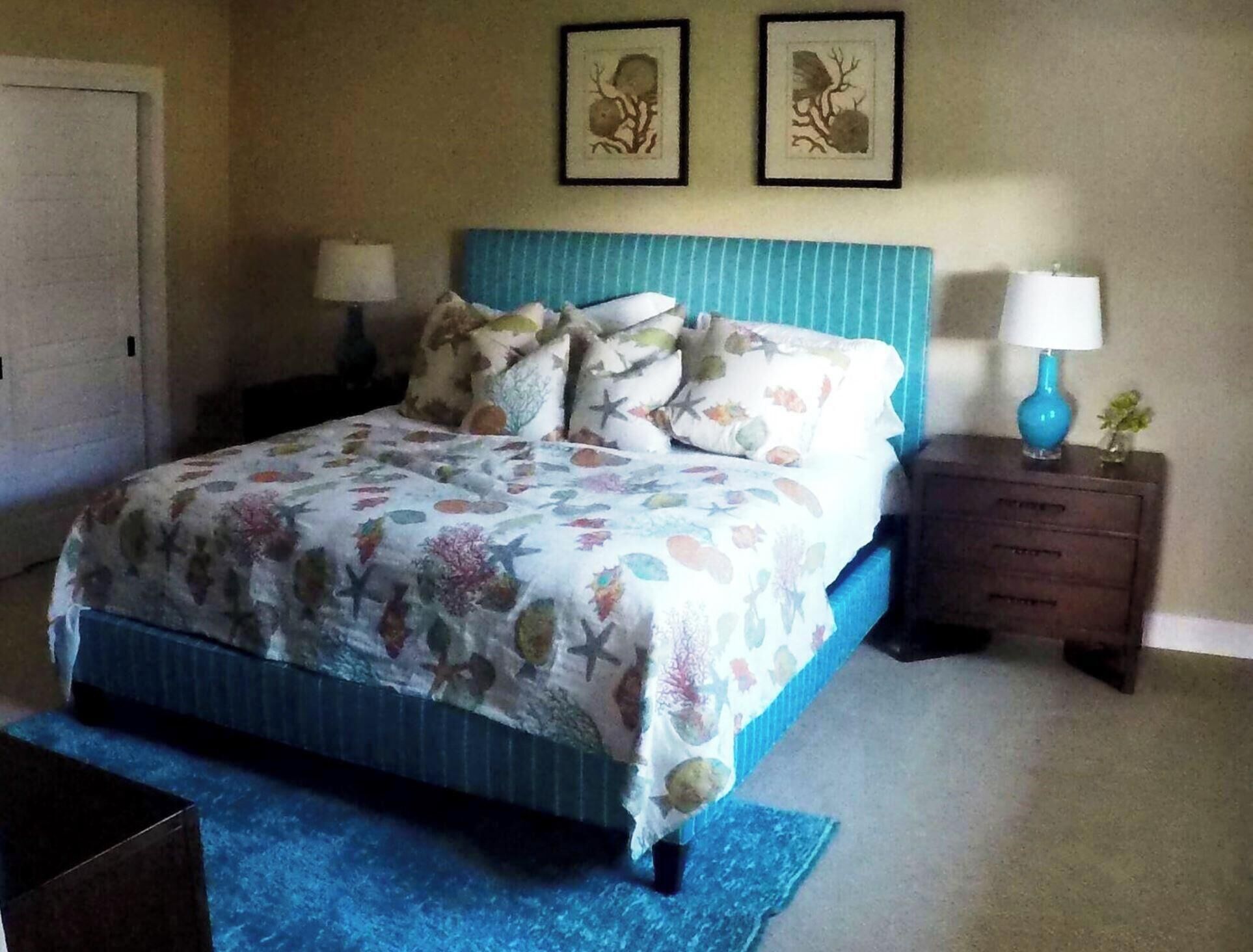 A bedroom with a bed, nightstands, a dresser, and two wall-mounted pictures.