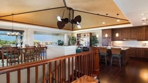 A spacious living area with a wooden staircase, a dining area, and a kitchen with wooden cabinets. - Stunning 4  bed, 3 1/2 bath Mauna Lani home near beach, golf (Waimea)