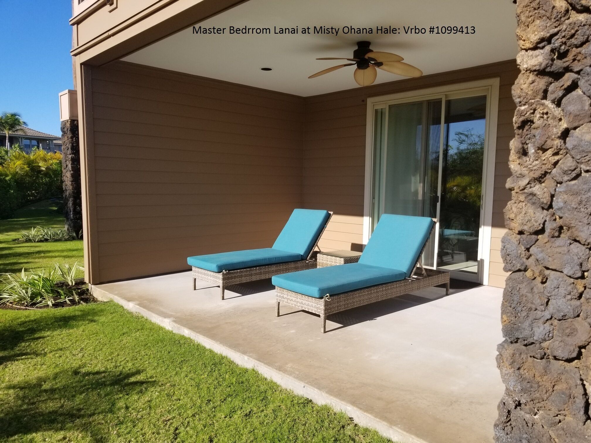 A master bedroom lanai at Misty Ohana Hale with two lounge chairs and a ceiling fan.