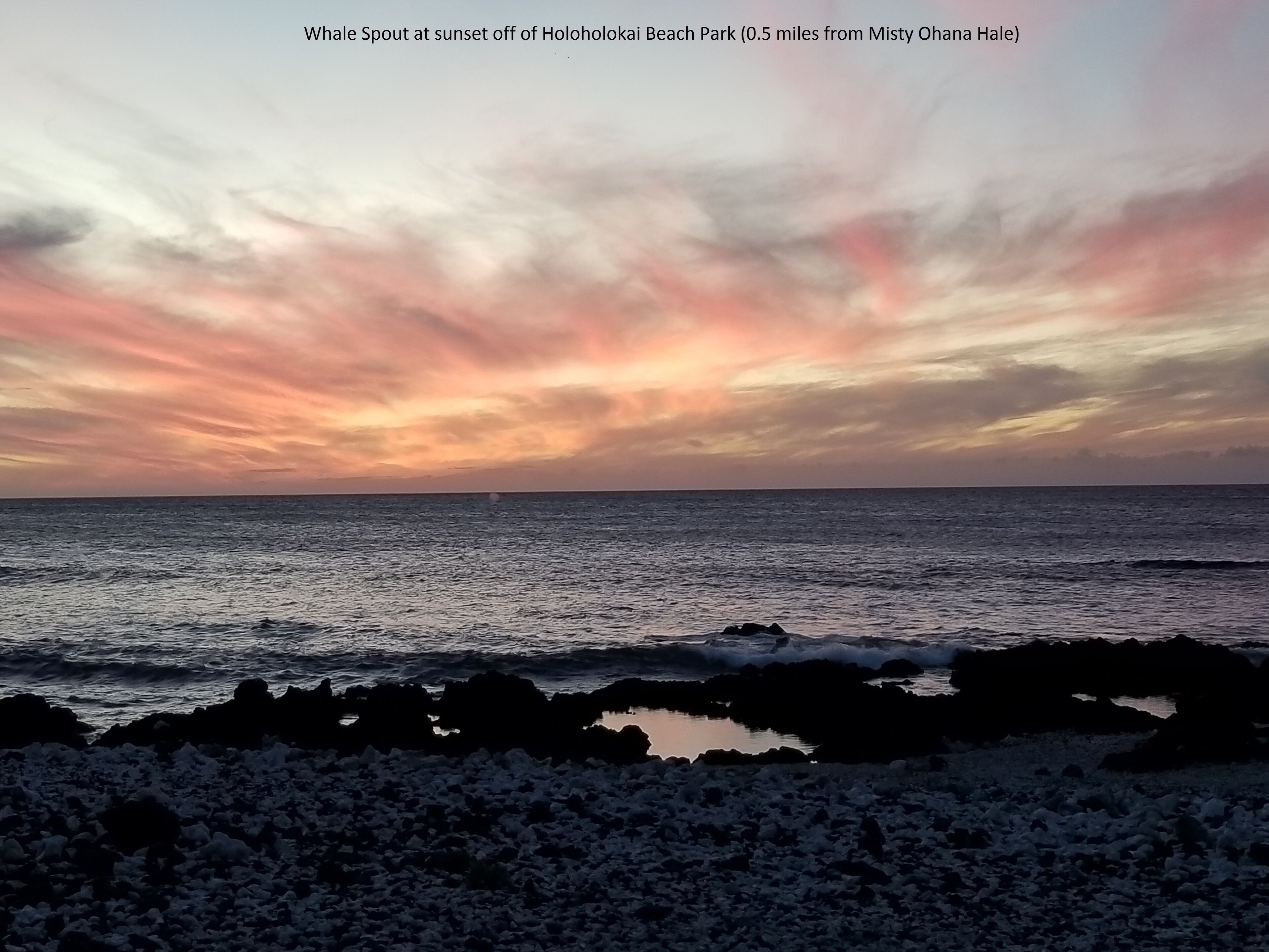 A sunset over the ocean with a rocky shoreline.