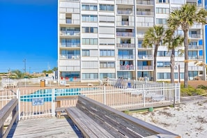 A multi-story hotel with balconies, a pool area, and palm trees.