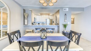 Un espace repas comprenant une table, des chaises, un lustre et une grande fenêtre.