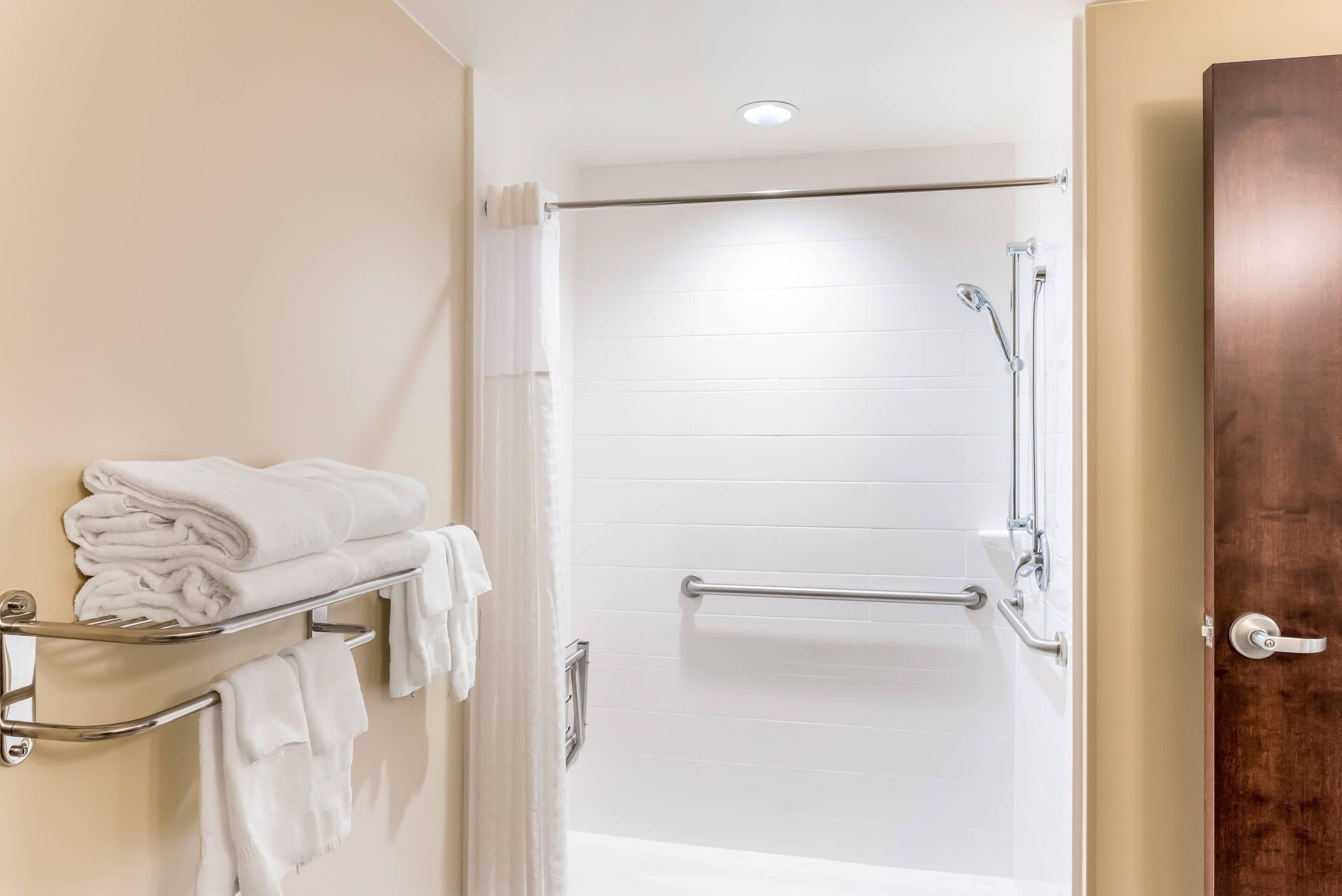 Une salle de bain moderne avec une douche à l’italienne, un porte-serviettes et une porte en bois.