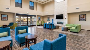 A spacious lobby with blue sofas, a reception desk, and a flat-screen TV mounted on the wall. - Comfort Inn & Suites Zion Park Area (Hurricane)