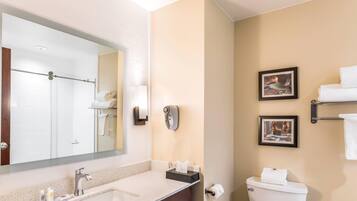 A modern bathroom with a large mirror, two sinks, a toilet, and a towel rack.