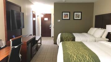 A hotel room with a bed, a desk, a chair, a television, and two framed pictures on the wall.