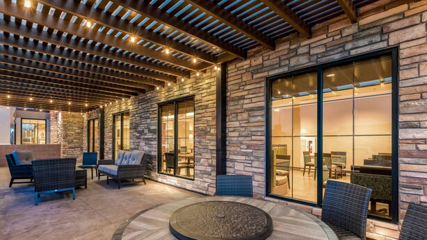 An outdoor seating area with stone walls, large windows, and a circular fire table. - Comfort Inn & Suites Zion Park Area (Hurricane)
