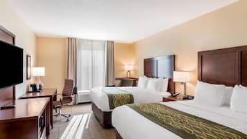 Habitación de hotel con dos camas, un escritorio, un televisor y una ventana con cortinas.