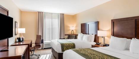 Habitación de hotel con dos camas, un escritorio, un televisor y una ventana con cortinas.