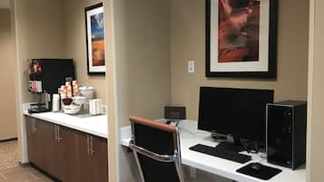 Une chambre d’hôtel équipée d’un bureau, d’un ordinateur et d’un coin café.