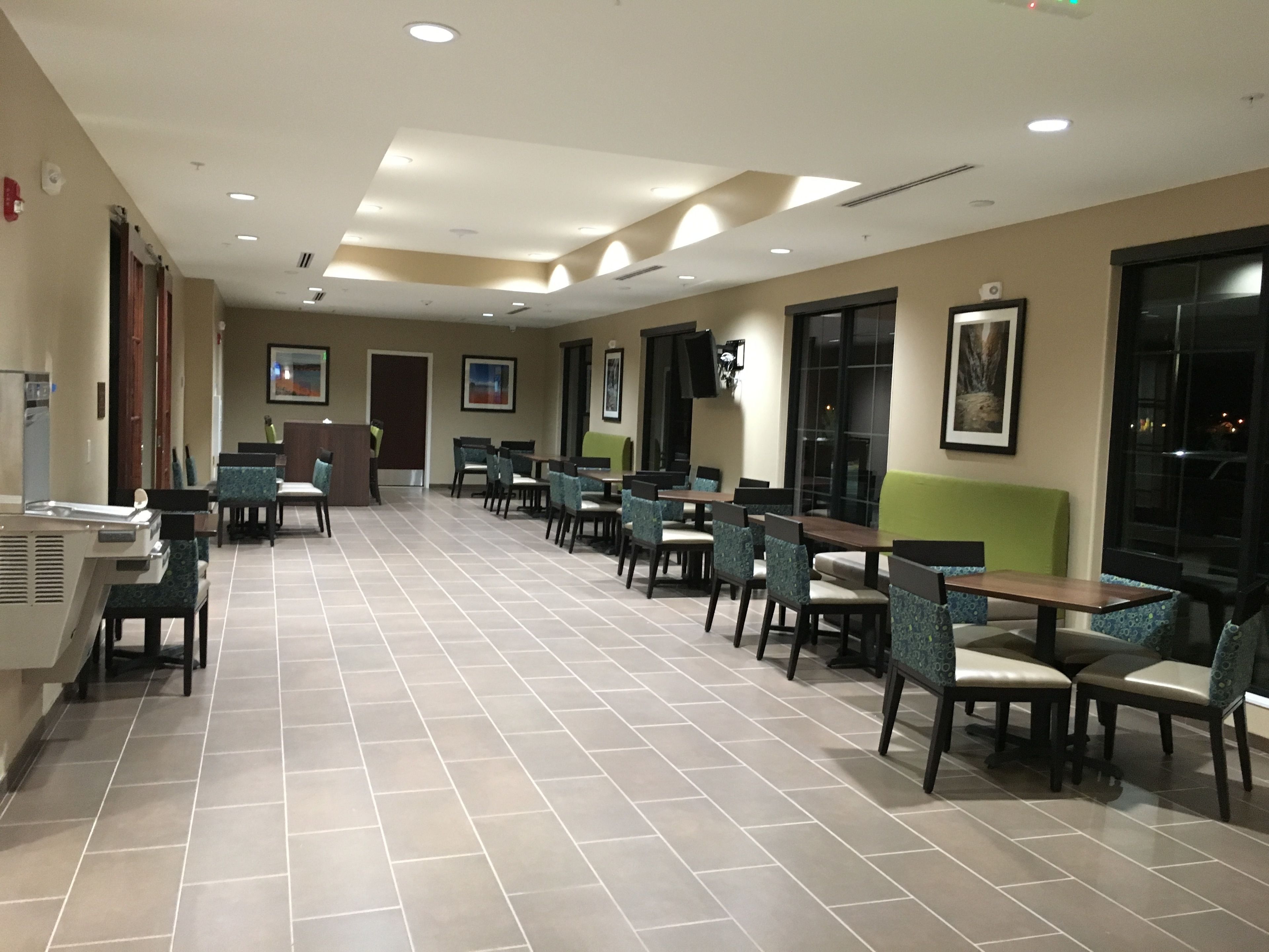 A spacious indoor area with multiple tables and chairs, a reception desk, and a television mounted on the wall.