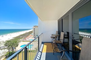 Un balcón con vistas a la playa, la piscina y los edificios del complejo turístico.