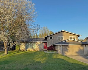 A residential house with a red door, a garage, and a well-maintained lawn. - Spokane Indoor Pool Home (Spokane)