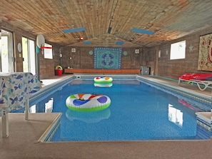 An indoor swimming pool with wooden ceiling and walls, a colorful mural, and inflatable rings. - Spokane Indoor Pool Home (Spokane)