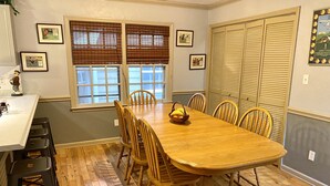 A dining room with a wooden table and chairs, a window with blinds, and a framed picture on the wall. - Golfers getaway - putting green, billiards, bar, arcade , poker table and more (Pinehurst)