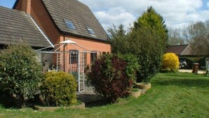 A house with a sloped roof, a fenced garden, and various shrubs. - Rosebarne Bed & Breakfast (Haverhill)