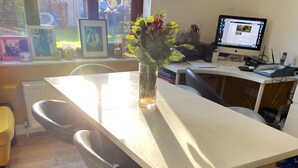 A dining table with four chairs, a vase with flowers, and a computer on a desk. - Rosebarne Bed & Breakfast (Haverhill)