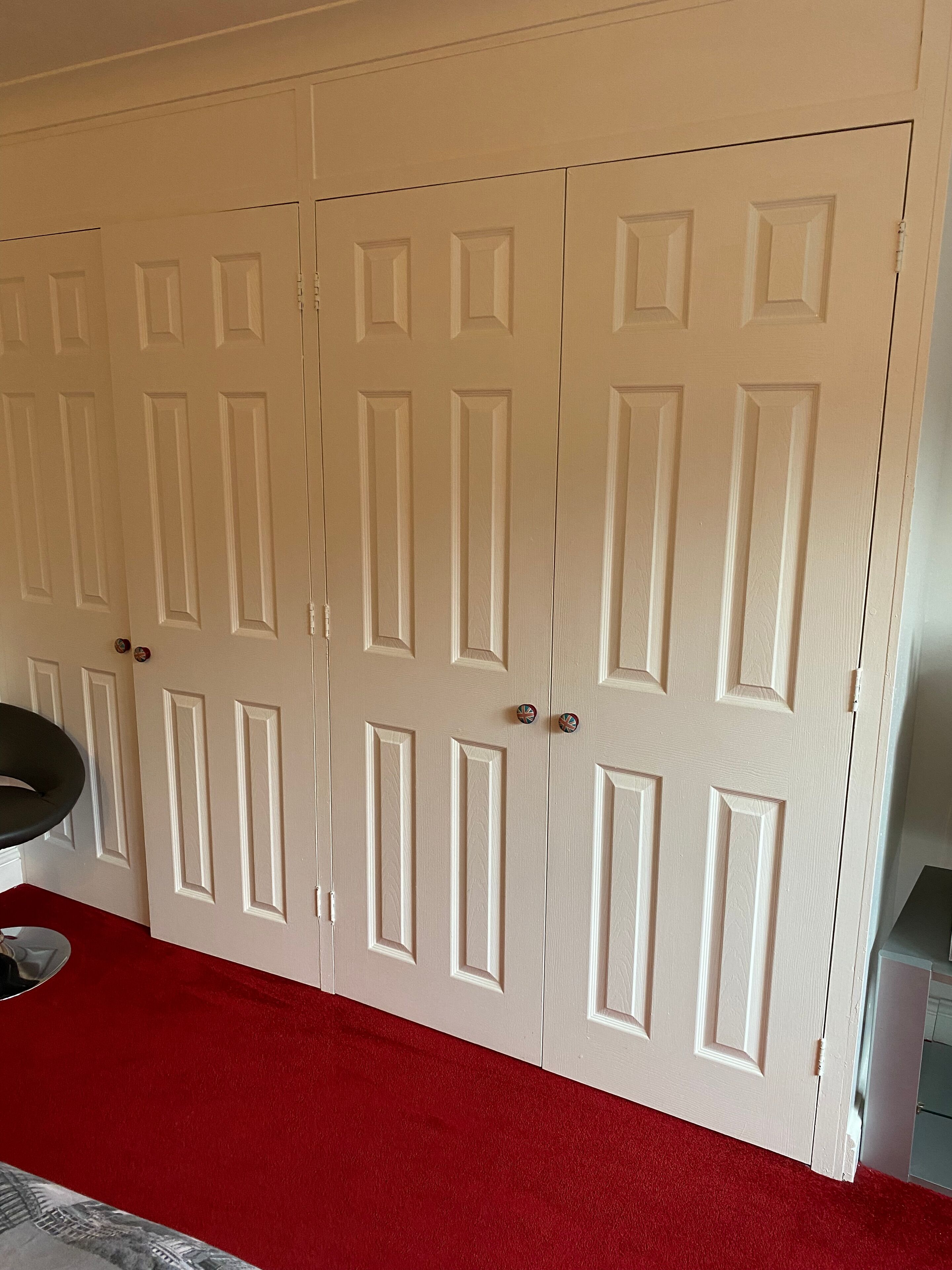 A set of white double doors with a red carpet leading to them.