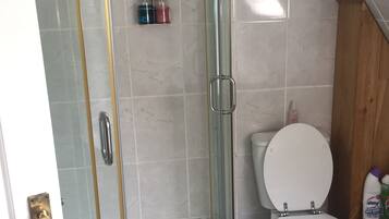 A bathroom with a glass-enclosed shower, a white toilet, and a wooden cabinet.