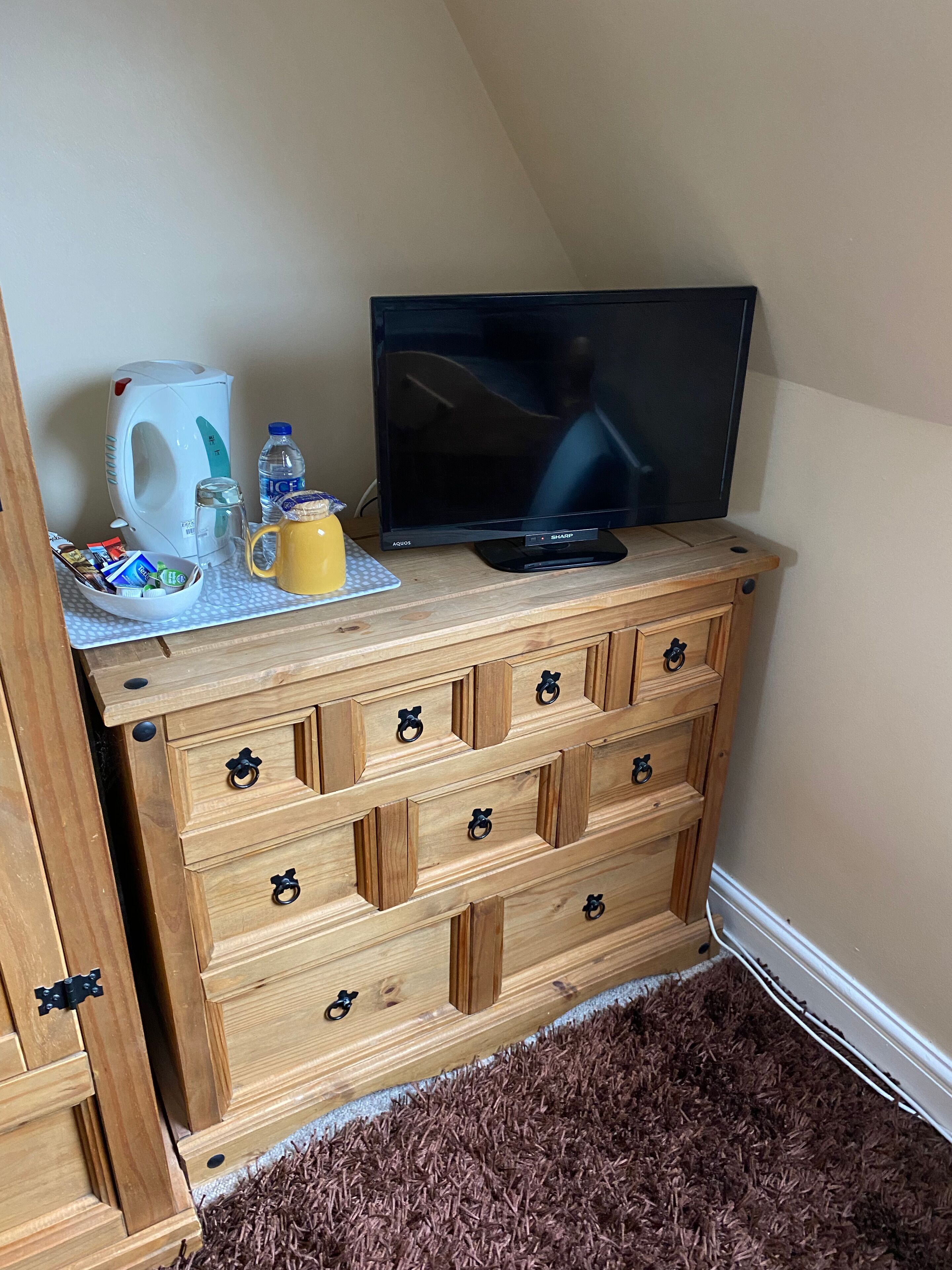 A wooden dresser with drawers and a flat-screen TV on top.