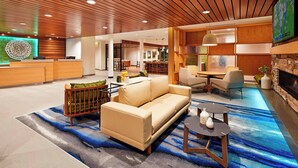 A modern hotel lobby with a reception desk, seating area, and a dining space. - Fairfield by Marriott Inn & Suites Indio Coachella Valley (Indio)