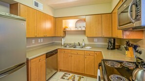 A kitchen with wooden cabinets, a stainless steel refrigerator, a microwave, a stove, and a sink. - ABQ Uptown Condo near I-40, 2bd/1ba, AC! (Albuquerque)