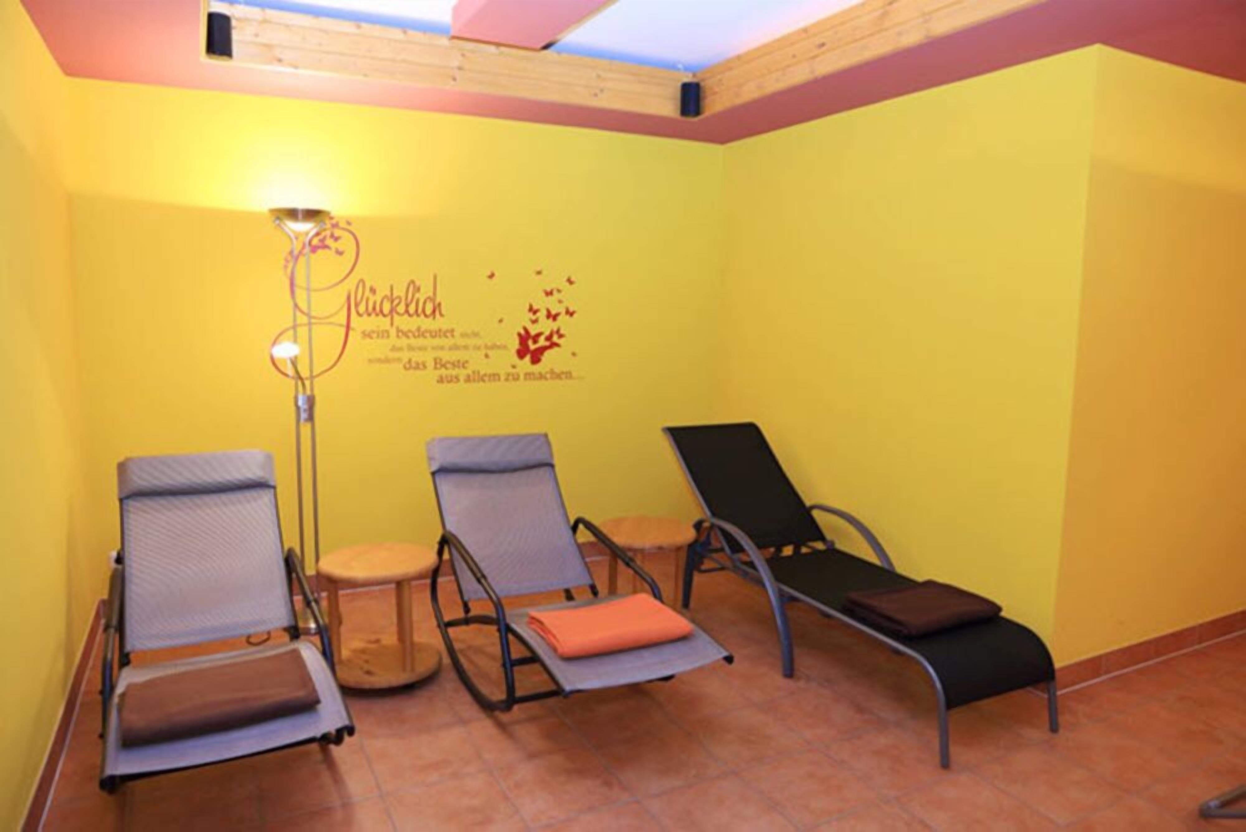 A room with three reclining chairs, a floor lamp, and a wall with a motivational quote.
