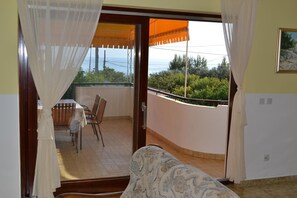 Un balcone con tavolo e sedie, vista sul mare e un quadro appeso alla parete.