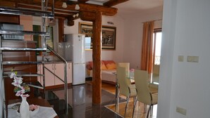 Uma cozinha com área de jantar, escada e uma cama ao fundo.
