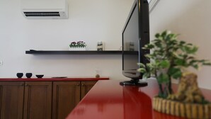 A kitchen with a red countertop, a black TV, a white air conditioner, and a shelf with books and a plant. - Welc-oM Panoramic (Padova)