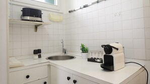 A modern kitchen with white cabinets, a stainless steel sink, a coffee maker, and a small potted plant. - Welc-oM Panoramic (Padova)