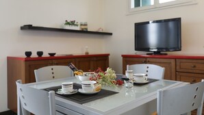 A dining area with a table set for two, a television, and a shelf with kitchen items. - Welc-oM Panoramic (Padova)