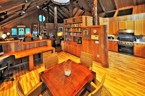 A cozy, wood-furnished interior with a dining area, kitchen, and bookshelves. - Gramma's 4BR Home, Lake, Wooded, Hot Tub, Swim, Swings, Gated Estate, Gorgeous (Friday Harbor)