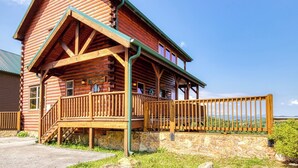Ein Blockhaus mit Veranda, Steinunterbau und Blick auf die Landschaft.