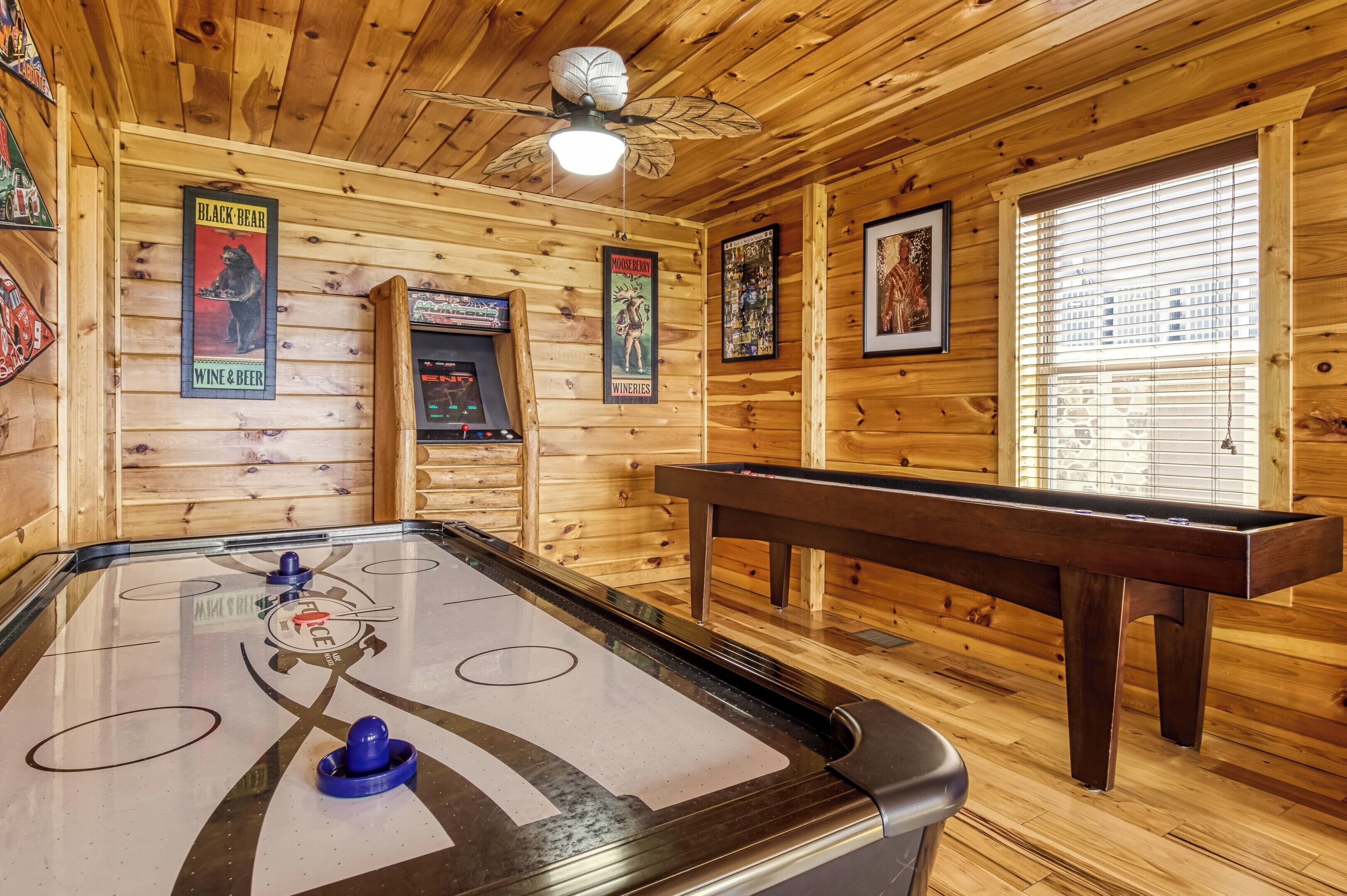 A wooden interior with a pool table, a ceiling fan, and wooden walls.