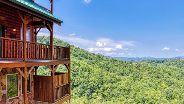 Eine Holzhütte mit einem Balkon mit Blick auf ein bewaldetes Gebirge.