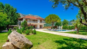 A two-story house with a balcony, a swimming pool, and a mountainous backdrop. - Villa Agricola (Zakynthos)