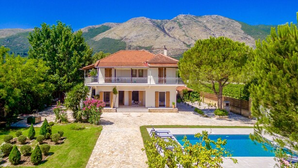 A two-story house with a balcony, surrounded by a well-maintained garden and a swimming pool. - Villa Agricola (Zakynthos)