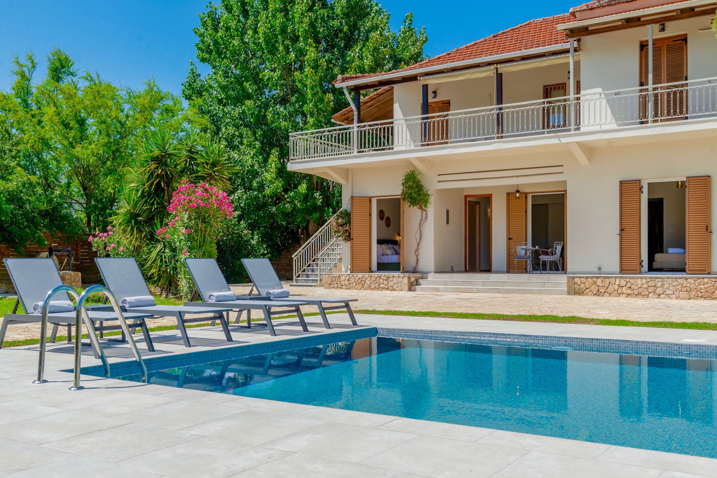 A two-story house with a swimming pool, outdoor seating, and a balcony.