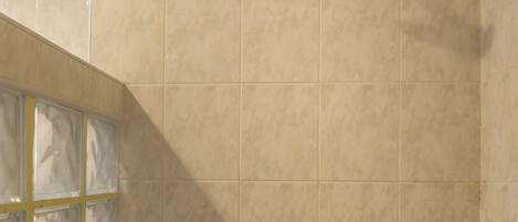 A shower with a glass door and a wall-mounted control panel.