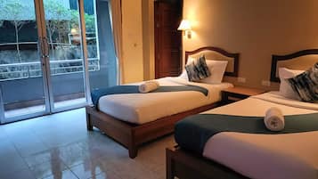 A hotel room with two beds, a sliding glass door to the outside, and a nightstand with a lamp.