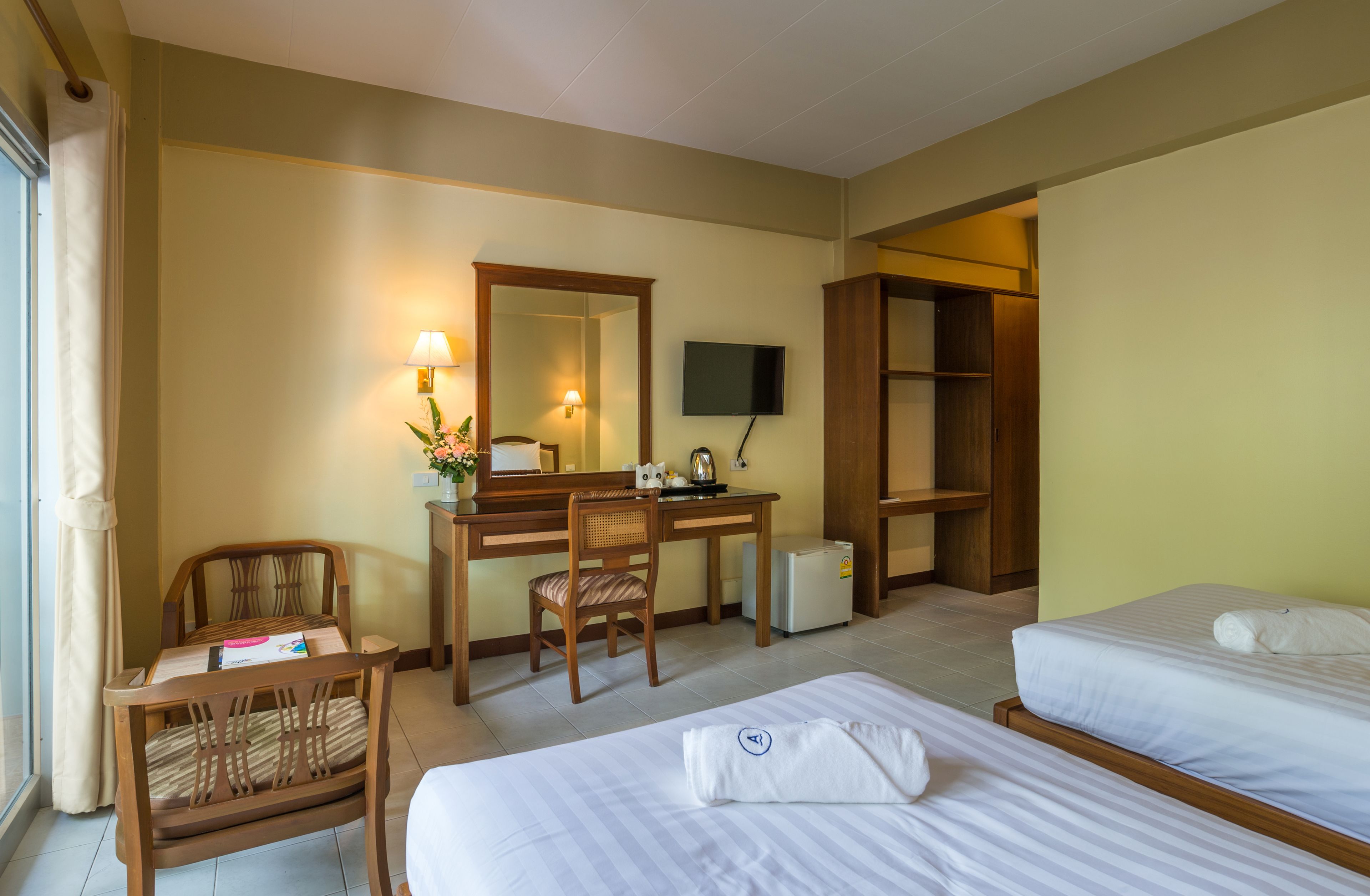 A hotel room with two beds, a desk with a chair, a television, and a wardrobe.