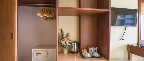 Quarto bem organizado com um guarda-roupa de madeira, uma pequena mesa com chaleira, xícaras e um arranjo de flores.