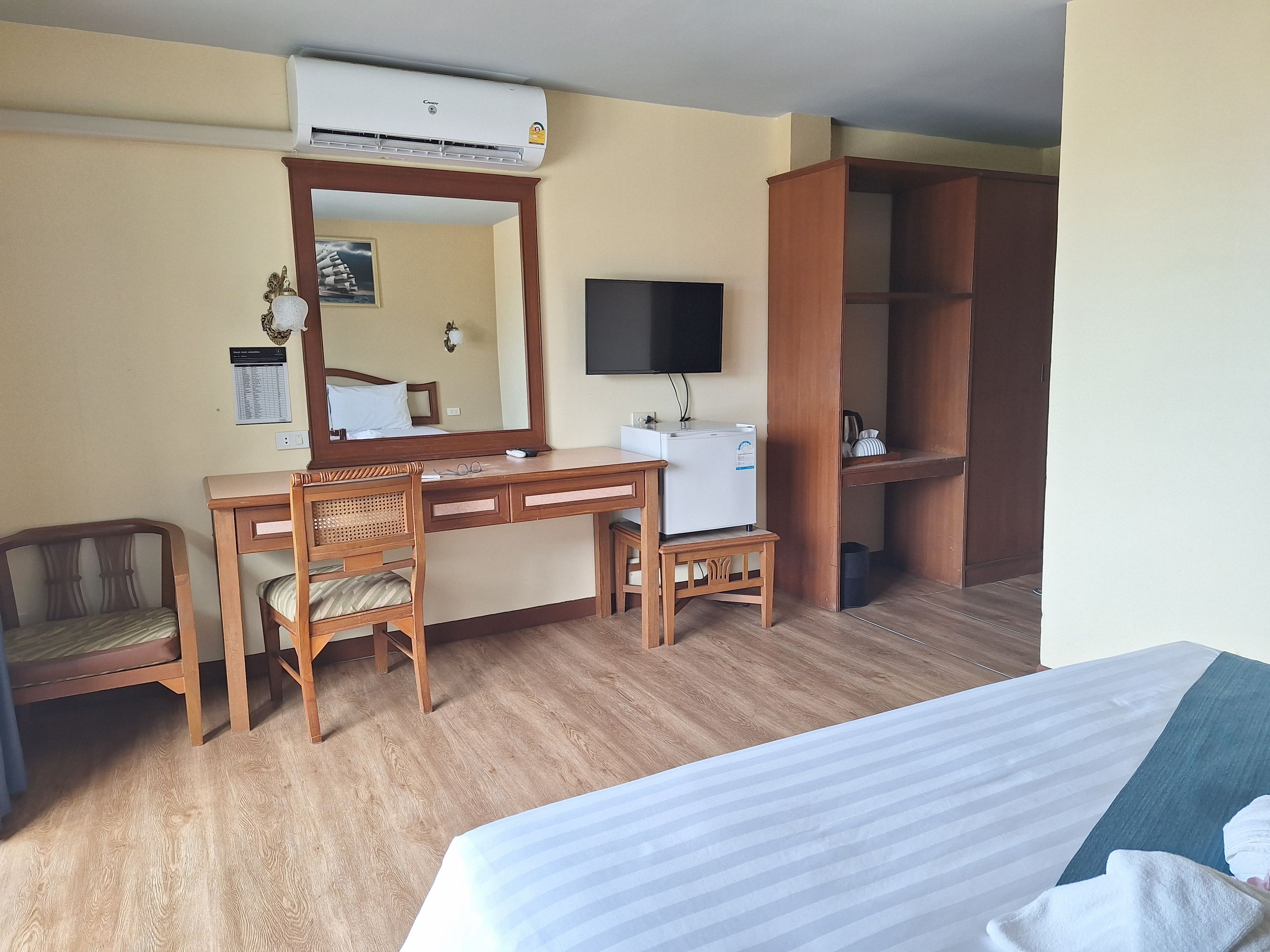 Une chambre d’hôtel équipée d’un lit, d’un bureau, d’une chaise, d’une armoire et d’un téléviseur.