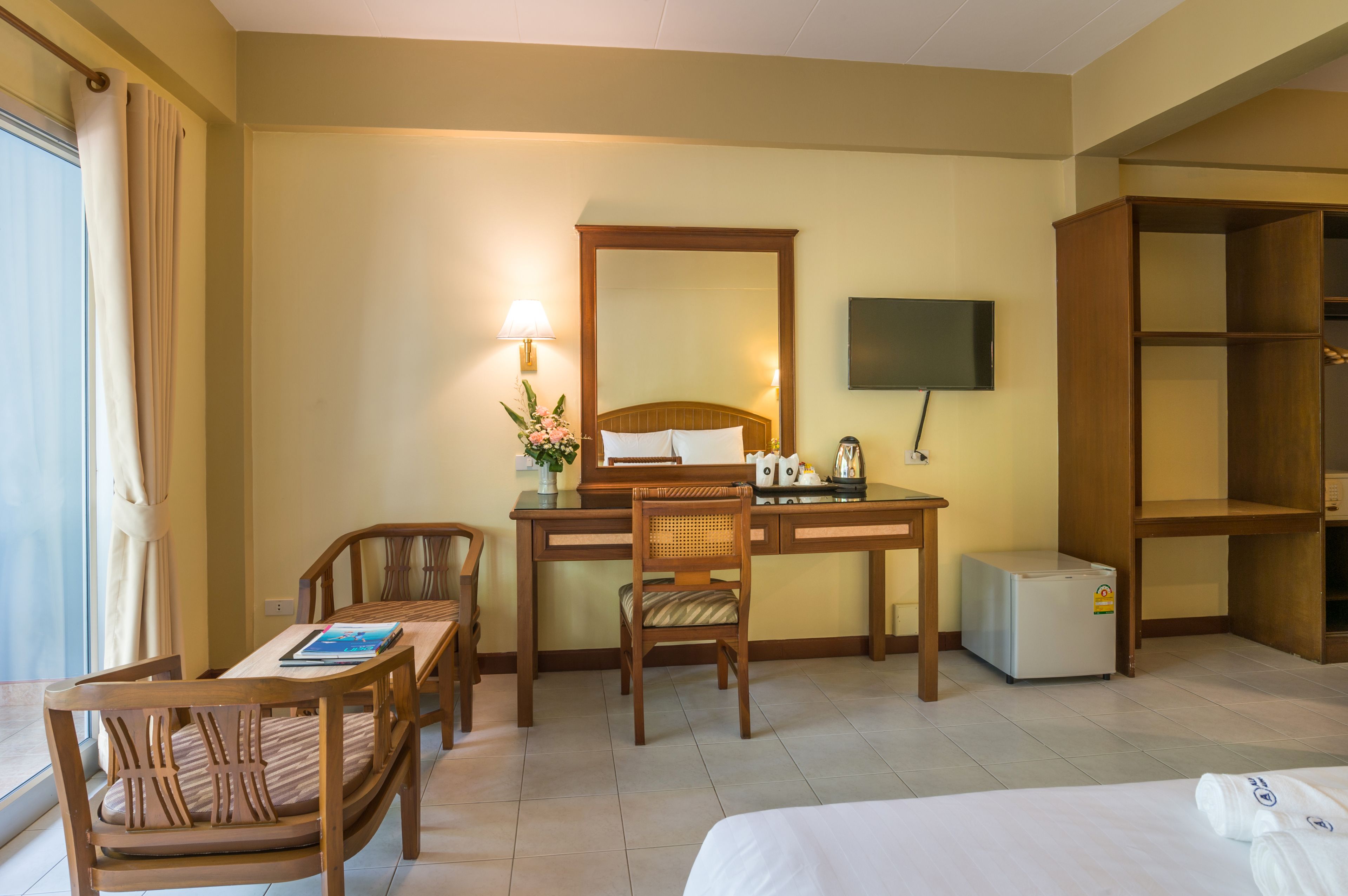 Une chambre d’hôtel équipée d’un lit, d’un bureau, d’une chaise, d’un petit réfrigérateur, d’une télévision et d’une bibliothèque.