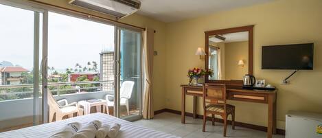 Une chambre d’hôtel comprenant un lit, un bureau, une chaise, une télévision et un balcon avec des chaises.